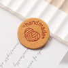 A round, tan PU leather label with the word handmade stamped in red on a white background.