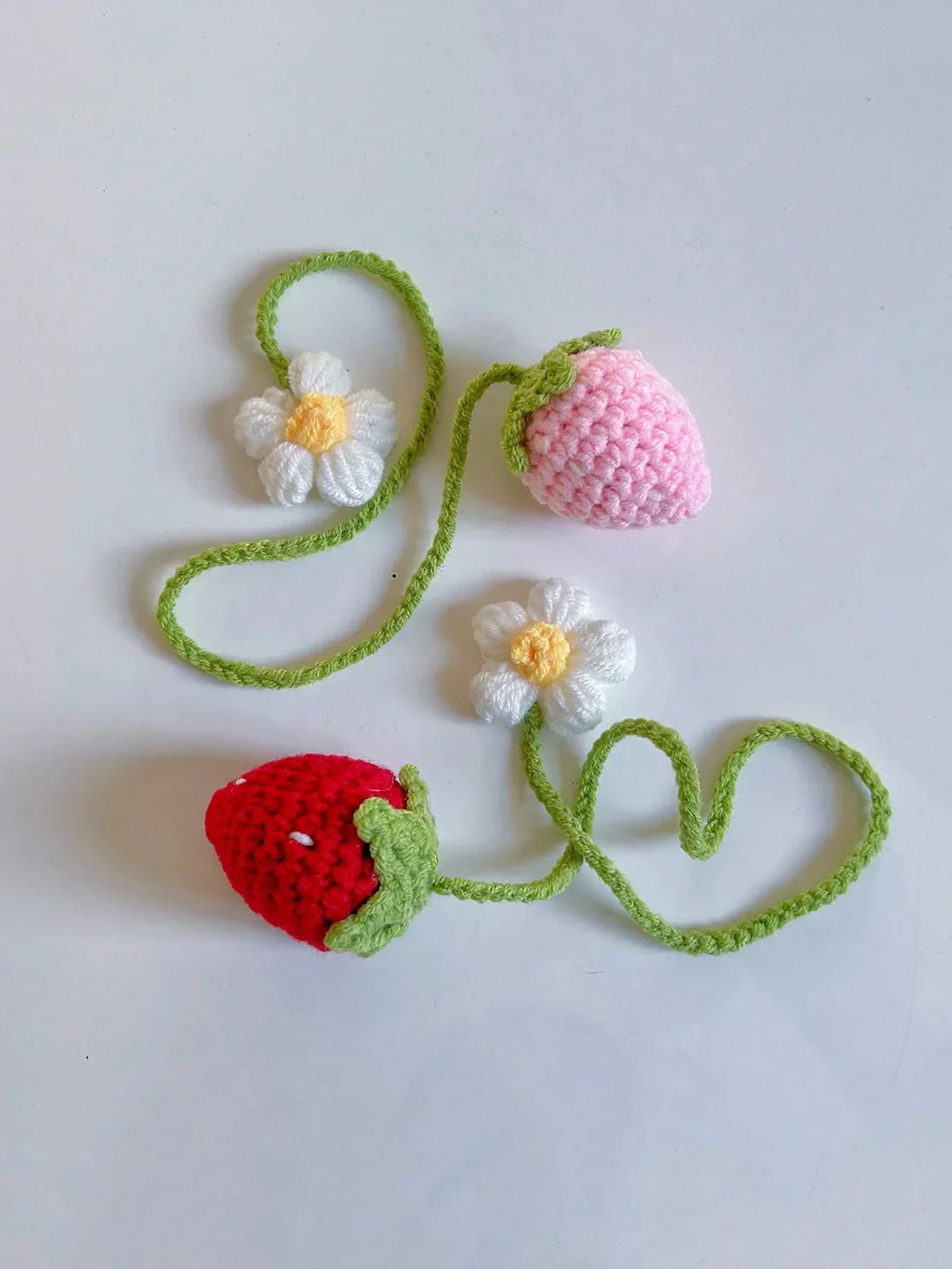 Handmade crochet strawberry with a flower and green stem, used as a mirror pendant.