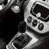 Close-up of a plush car gear shift and handbrake cover set inside a vehicle cabin.