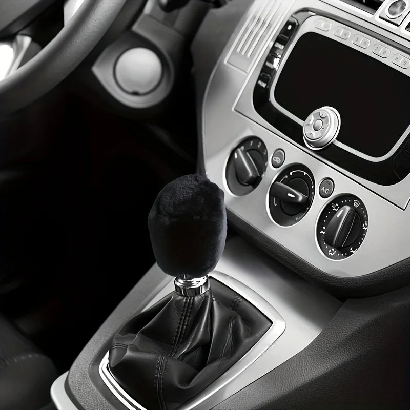 Close-up of a plush car gear shift and handbrake cover set inside a vehicle cabin.