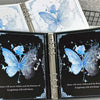 A photo album featuring butterfly designs on the cover pages, with a silver binding.
