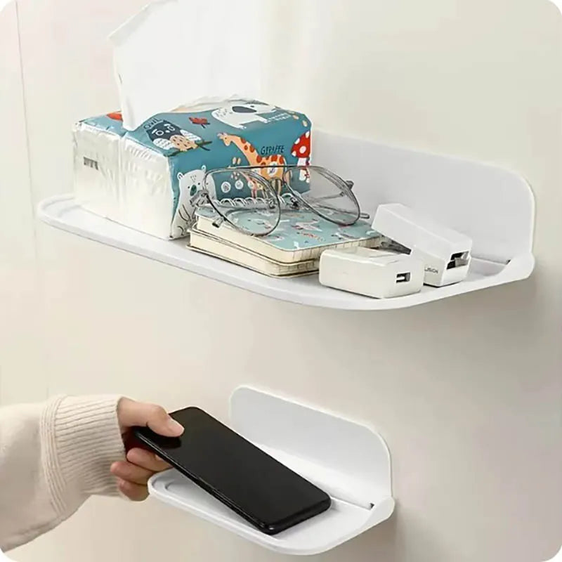 A white wall shelf holds various items including a box, eyeglasses, and a smartphone.
