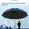 A large black umbrella is held up against a blue sky above a cityscape.