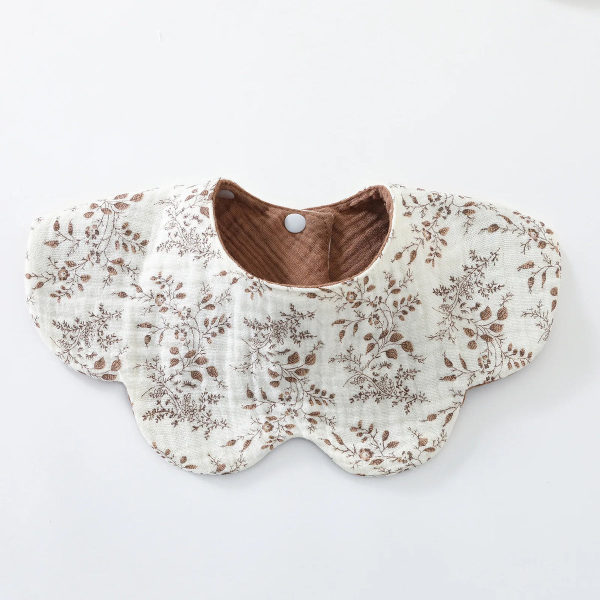 A beige cotton baby feeding bib with a brown floral pattern and a padded opening.