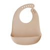 A light beige silicone baby bib with a catch pocket and a curved shape.
