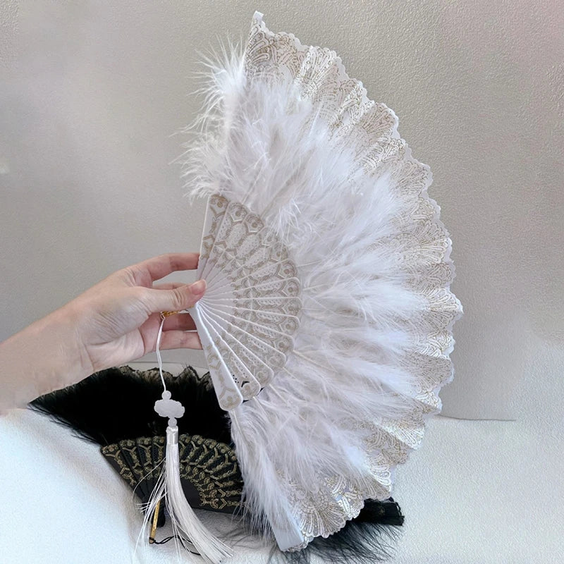 A white folding fan with lace trim and a golden edge is held by a hand against a light background.