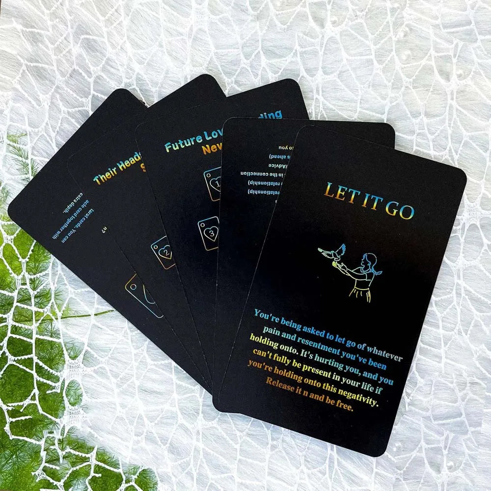 A stack of black oracle cards titled Future Love, Never, and Let It Go are displayed on a white surface.