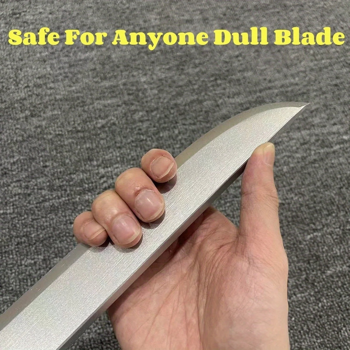 A hand holds a full-size metal blade, safe for anyone, with a dull edge.
