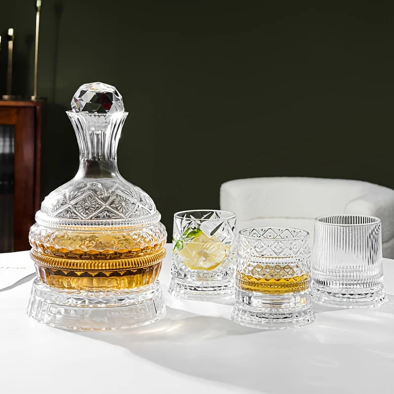 A handcrafted crystal wine decanter with a rotating aerator sits on a white table next to various drinking glasses.