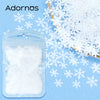 A clear plastic bag filled with white glitter or sanding sugar next to snowflake cutouts on a blue background.