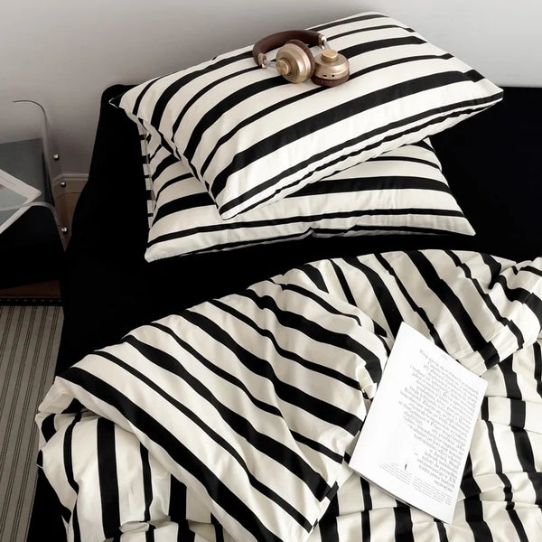 A black and white striped duvet cover set with a gold-toned brass object resting on top.