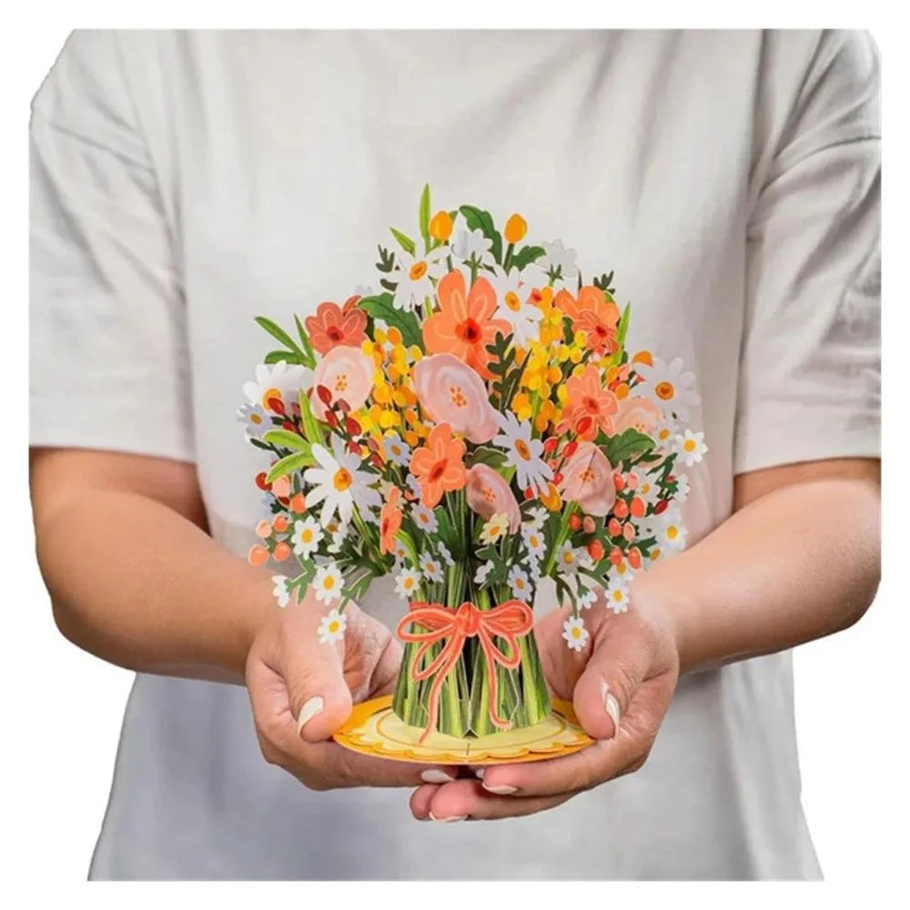 A hand holds a vibrant bouquet of orange, yellow, and white cherry blossoms and flowers.