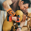 A man is using an orange magnetic wrist strap tool to hold small tools while working on something.