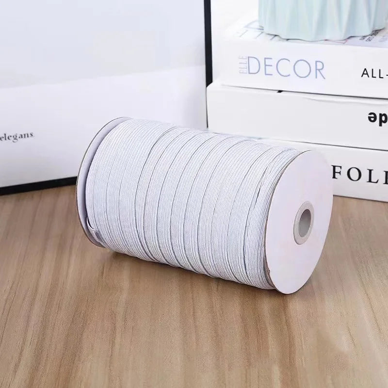 A roll of white polyester elastic bands for sewing and crafts placed on a wooden surface.