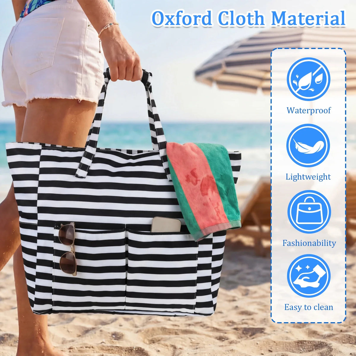 Une personne tient un sac de plage en toile rayée noir et blanc avec une poche mouillée sur une plage de sable.