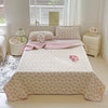 A pink floral quilted bedspread with a white border is displayed on a bed in a bright room.