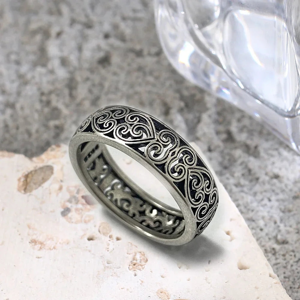Gros plan d'une bague en argent sterling vintage creuse florale posée sur une surface de pierre claire.
