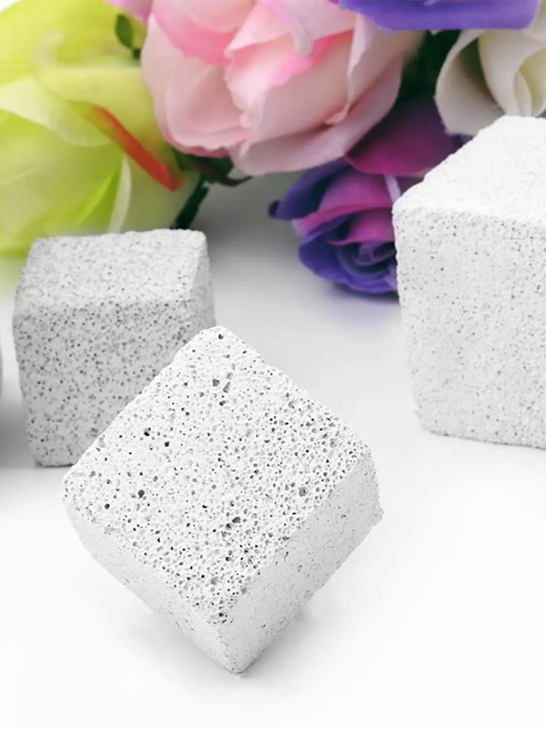 White natural mineral molar stones for small pets resting on a white surface with colorful flowers in the background