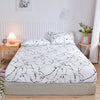 White fitted bed sheet with a black marble print displayed on a bed.