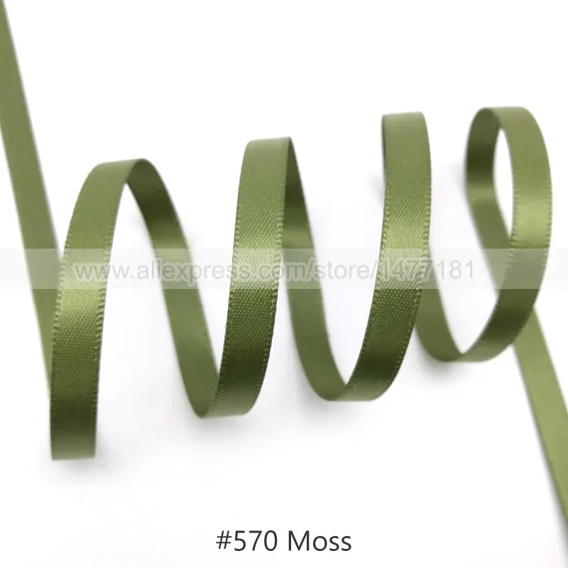 A roll of olive green moss colored satin ribbon coiled and unwound.