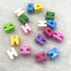 A collection of ten mixed alphabet letter beads in various colors like green yellow blue and pink arranged on a white surface