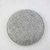A round, gray needle felting mat made of wool for crafting.