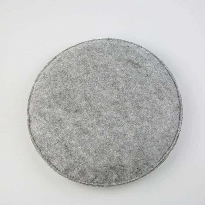 A round, gray needle felting mat made of wool for crafting.