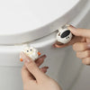 Hands are lifting a white cartoon toilet seat lifter handle.