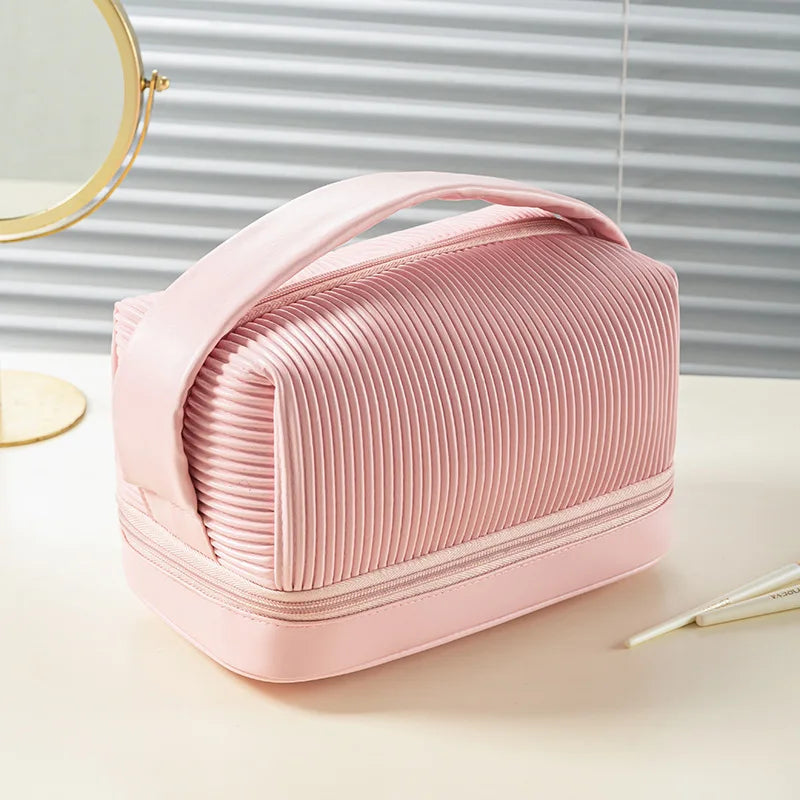 A pink PU leather makeup bag set with a hinged lid is shown on a light surface next to a mirror.