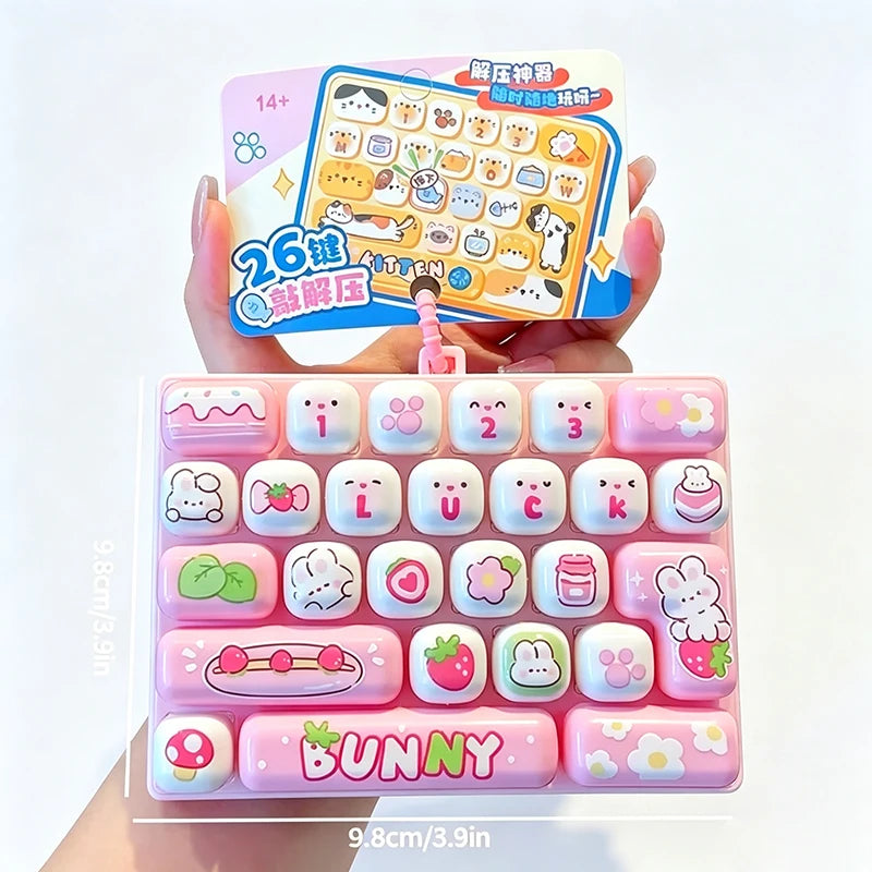 A pink set of 26 cartoon keycap fidget items and a yellow instruction card are held by a hand.