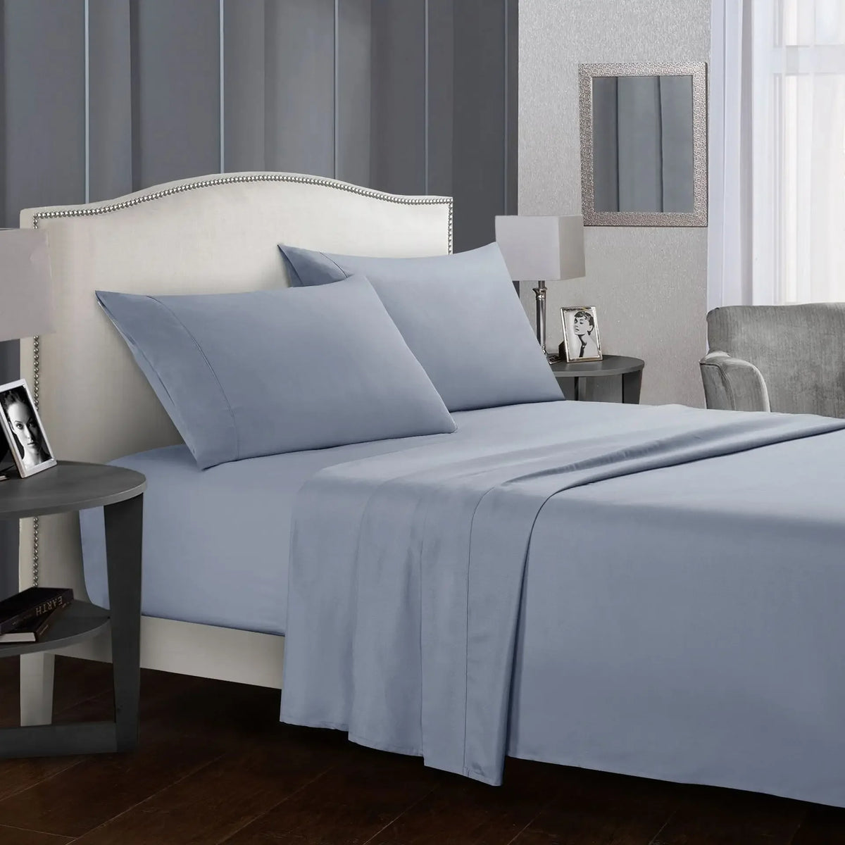 A light blue bedding set featuring a headboard, flat sheet, fitted sheet, and pillows in a bedroom setting.