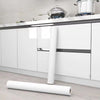 A roll of glossy self-adhesive vinyl wallpaper for waterproof home decor lying on a light wooden surface.
