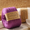 Purple pure cotton yarn skein for knitting and crochet displayed on a wooden surface.