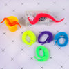A collection of fuzzy wiggly worm magic trick items including an orange bowl, a red wiggly worm, and various colored elastic 