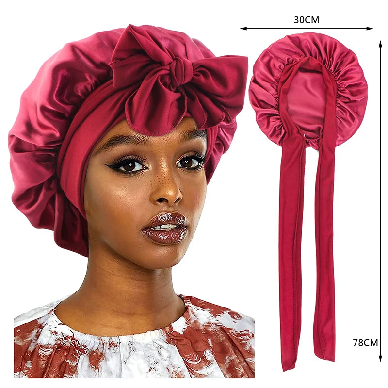 A model wears a silky satin sleep cap with a wide band in a deep rose color, shown alongside the product and its measuring ta