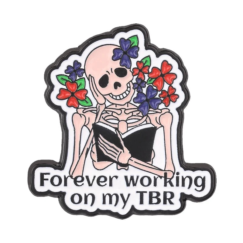 Enamel pin featuring a skull holding an open book with flowers, designed for book lovers.