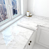 White marble countertop with a glass tile and cabinet featuring marble peel-and-stick wallpaper.