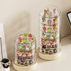 A clear, rotating display case holds various small collectible figures and keepsakes.