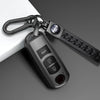 A close-up of a black TPU car key cover attached to a keyring and leather strap.