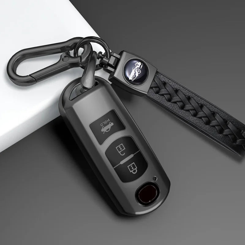 A close-up of a black TPU car key cover attached to a keyring and leather strap.