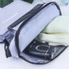 A purple hanging toiletry bag with a black zipper is open, revealing a white towel and a black bottle.