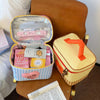A yellow insulated lunch bag with a pink cartoon design and an orange handle resting on a brown chair.
