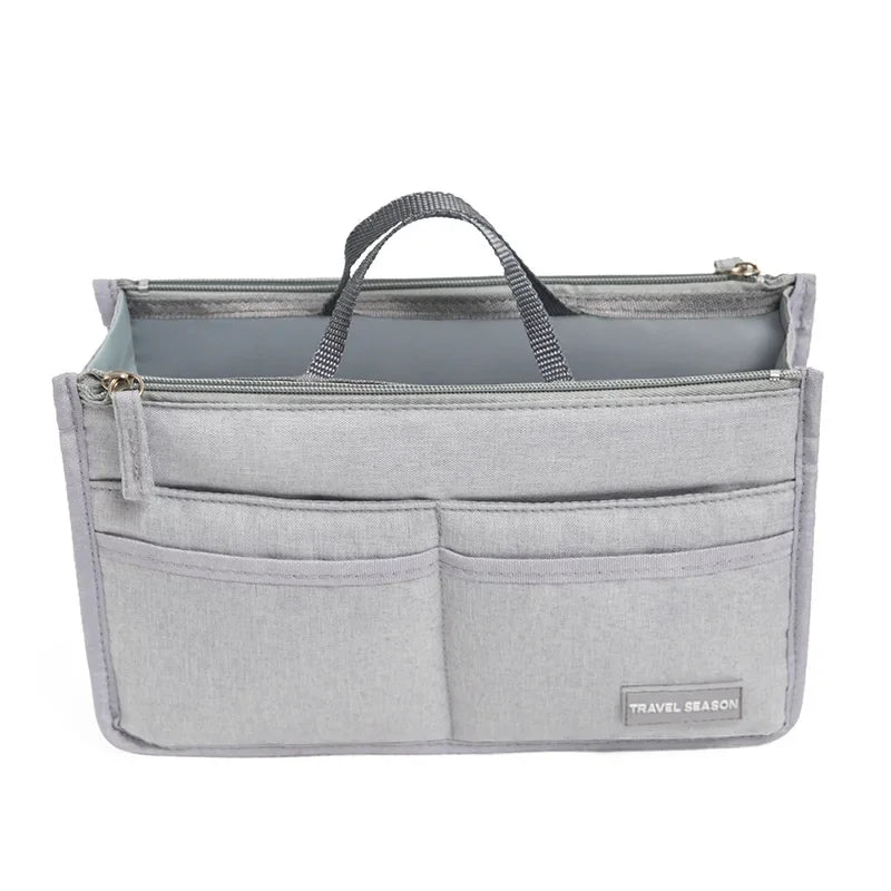A light gray purse organizer insert with multiple compartments and a fabric strap.