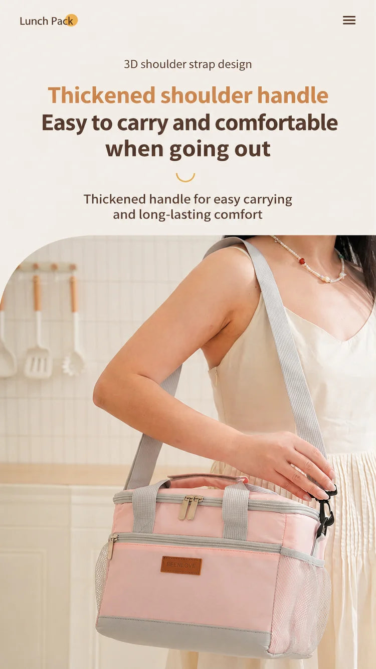 A woman is holding a pink and gray insulated lunch bag with a shoulder strap in a bright indoor setting.