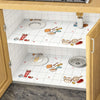 A kitchen cabinet interior showing white tiled shelves decorated with food and cooking utensils on a marble contact paper sur