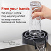 A hand is holding a clear glass cup being washed by a high pressure faucet glass rinser device.