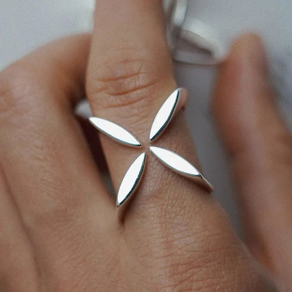 Nahaufnahme einer Hand mit einem verstellbaren Sterling-Silber-Kreuzblumenring am Finger.