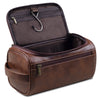 A brown leather toiletry bag with a hinged lid and zippered compartment is shown open.