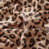 Flowing satin fabric with a brown and beige leopard print pattern