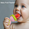 A baby is using a pink and green rotating silicone fruit feeder to feed a piece of fruit.